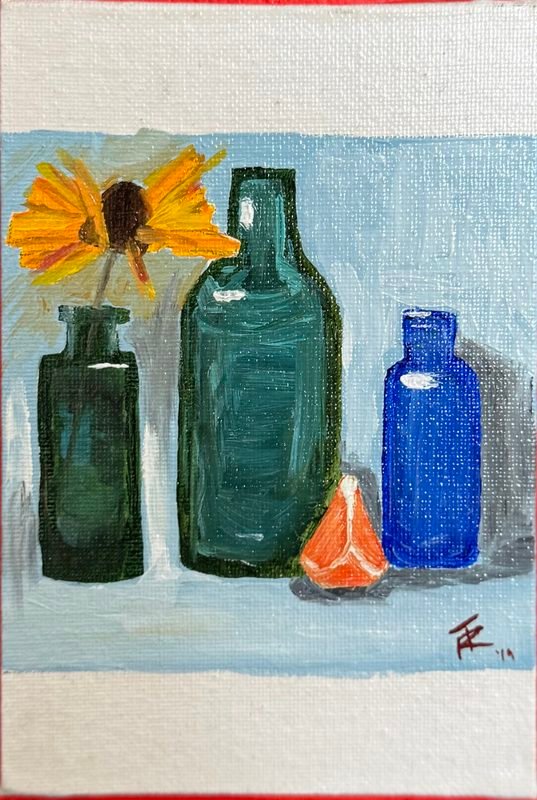 Still life of green and blue glass bottles with a sunflower and an orange slice