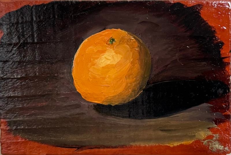 An orange on a dark ledge against black and red