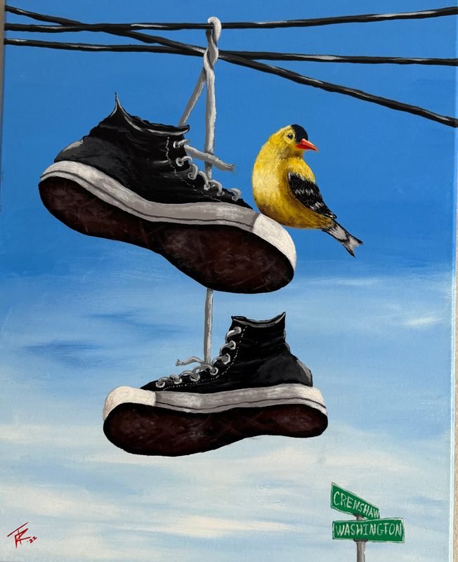 Sneakers hanging from power lines with a goldfinch perched on one, above a street sign