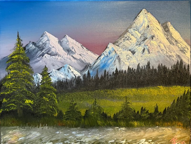 Snowy mountain peaks above a pine forest and a green meadow