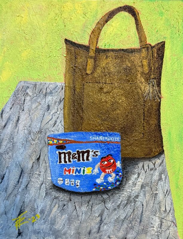Still life of a brown tote bag and a tub of M&M's Minis on a gray cloth, against lime green