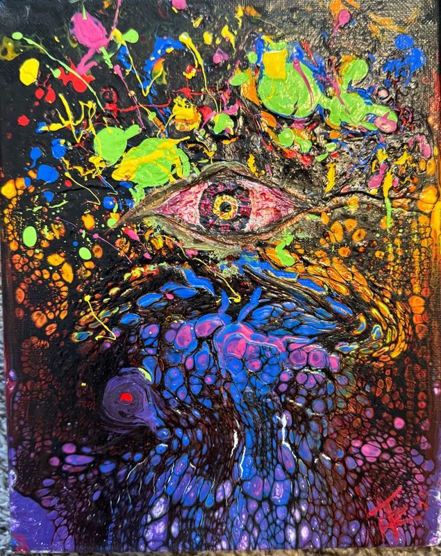 An eye surrounded by splatters and poured cells of neon color on black